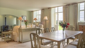 Een eetgedeelte met een houten tafel en stoelen, een bank en een open haard.