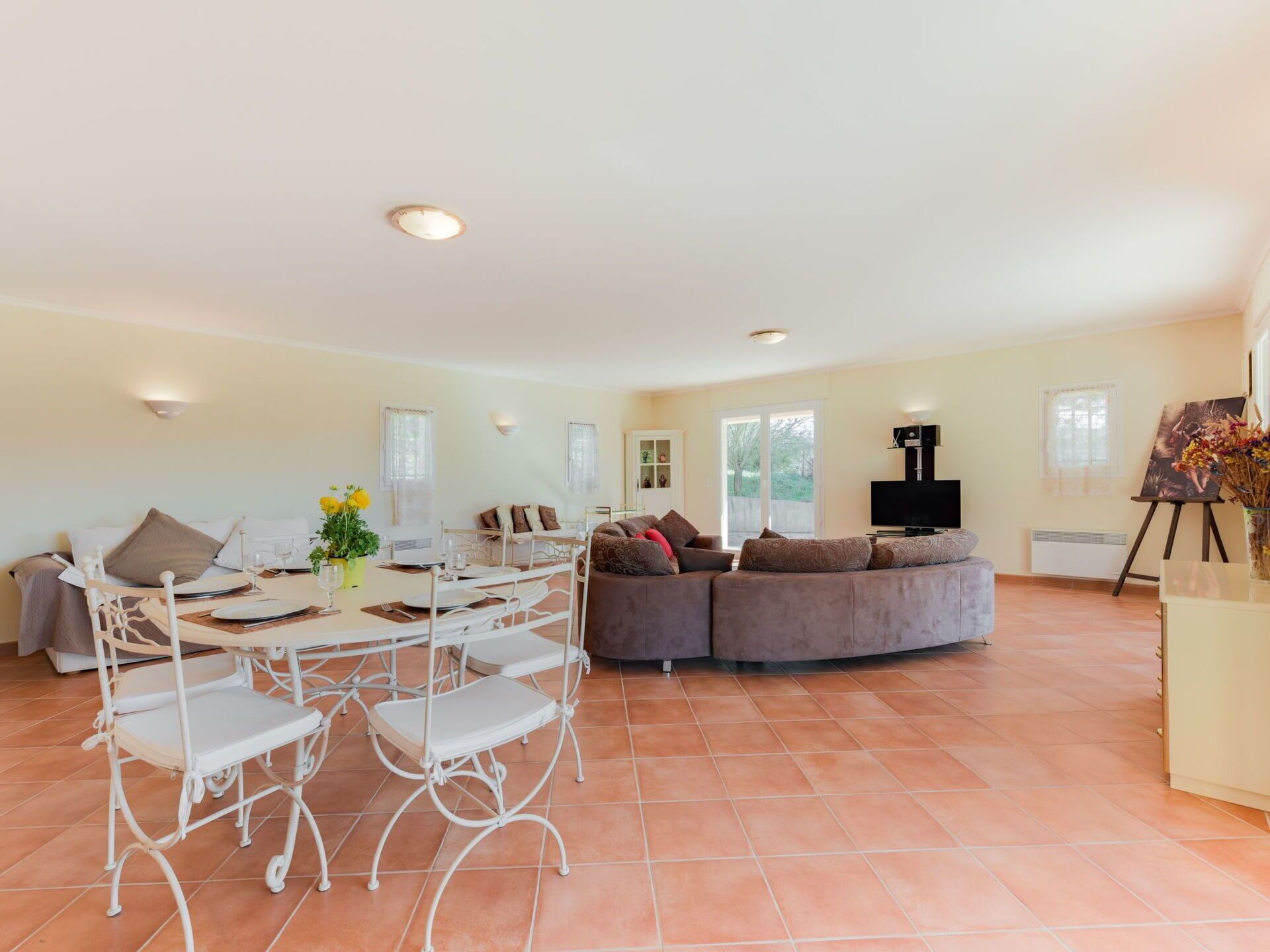 A spacious living area with a dining table set for four, a sofa, and a television.