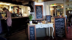 A restaurant interior with a bar area, menu boards, and a counter.