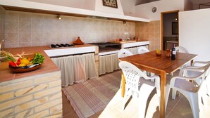Una cocina con una mesa y sillas de madera, estufa a gas y salpicadero de azulejos.