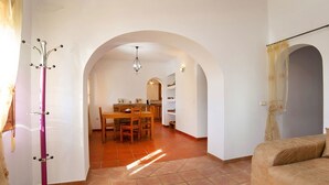 Amplia sala de estar con un sofá, una mesa de comedor con sillas y un perchero.