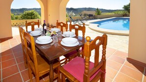 Mesa de comedor para cuatro personas con sillas, piscina y vista al paisaje.