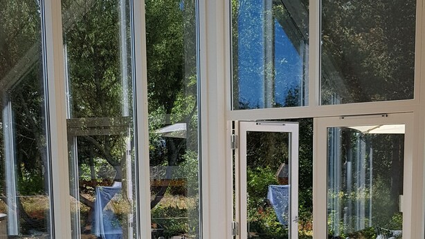 Una sala de estar moderna con un sofá modular, una mesa de centro redonda y puertas de cristal grandes que dan a una terraza al aire libre.