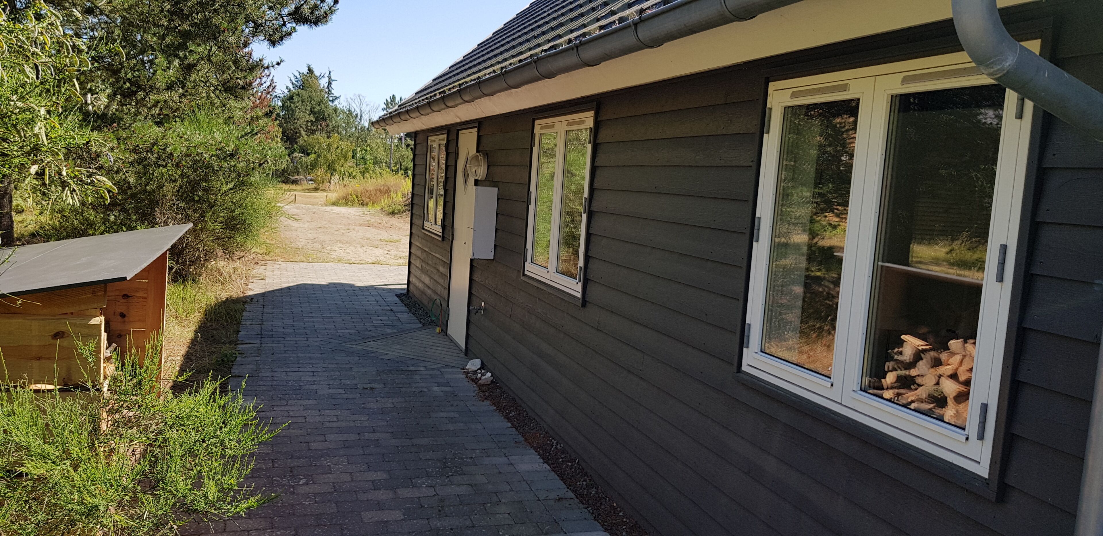 Una casa con entrada pavimentada y terraza de madera.
