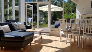 Una habitación iluminada por el sol con un sofá, una mesa redonda y un comedor con sillas.