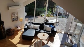 Una sala de estar acogedora con chimenea, un sofá, una mesita de centro y vistas a la terraza exterior.