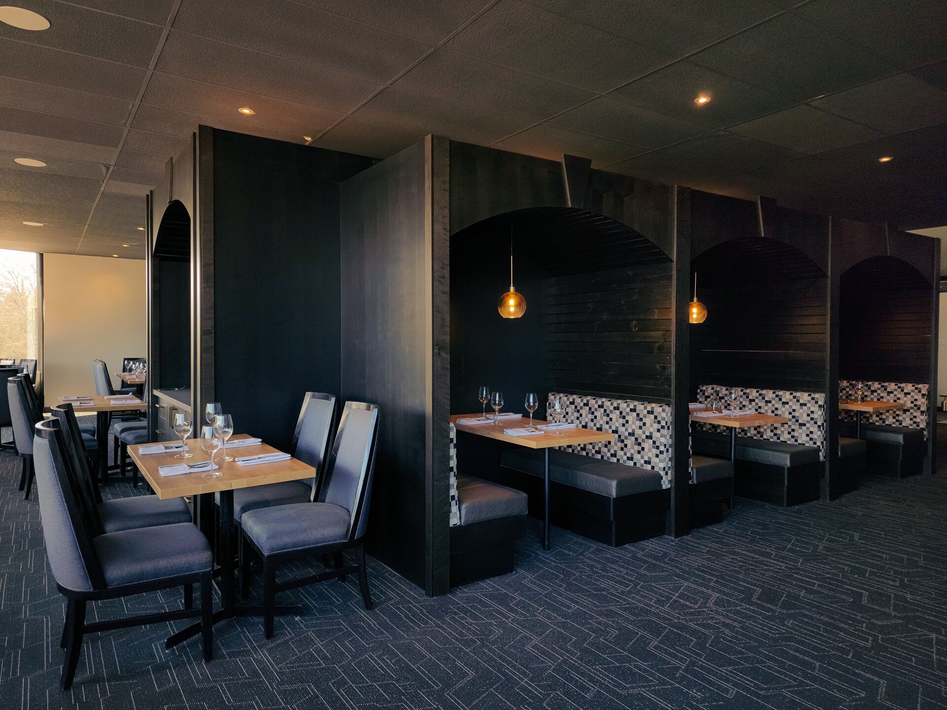 Un restaurante con cabinas y mesas, algunas con cojines a cuadros blanco y negro.