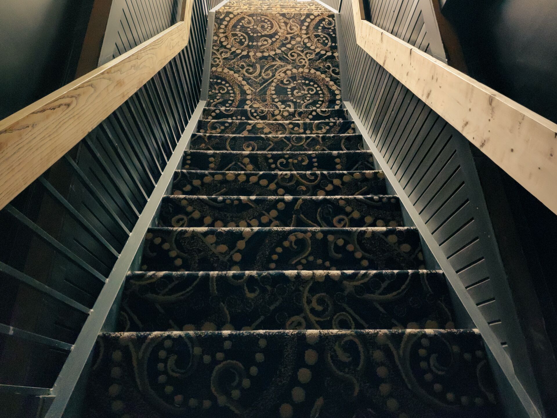 Una escalera con alfombra decorada y barandillas de madera.