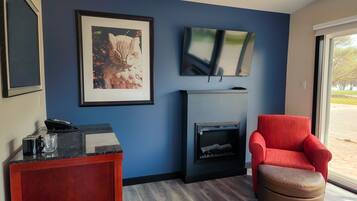 Un soggiorno moderno con una parete blu, un camino, una poltrona rossa e un televisore montato sopra.