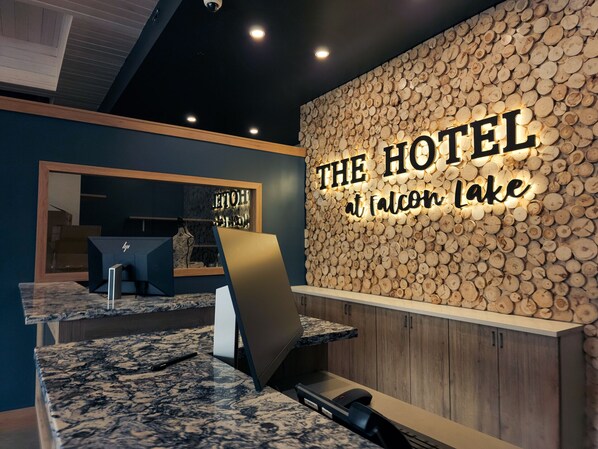 A reception desk with a wooden wall backdrop and a sign reading "The Hotel at Falcon Lake". - The Hotel at Falcon lake (Falcon Beach)
