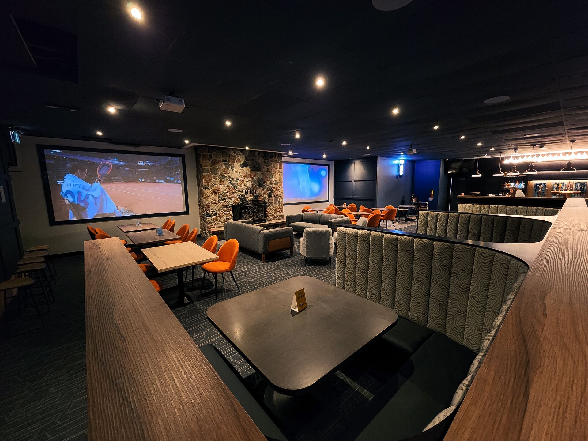 A cinema room with a large screen, seating, and a bar area.
