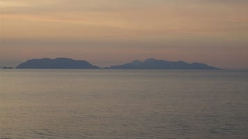 Ruhige See mit weit entfernten Landformen unter wolkenlosem Himmel.