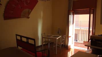 Une chambre d’hôtel comprenant un lit, une table à manger avec des chaises, un ventilateur et un balcon avec une balustrade.