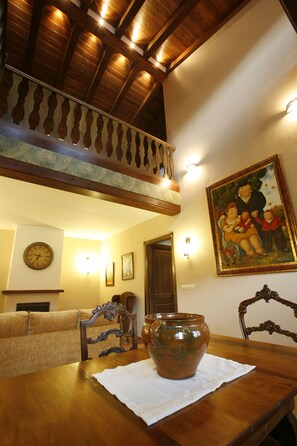 A dining area with a wooden table, a vase, and a painting on the wall.