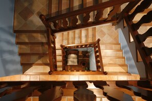 A staircase with a wooden railing and a view of a room with a bed and a window.