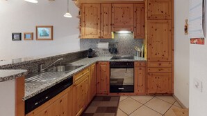 Eine Küche mit Holzschränken, Granitarbeitsplatten, einem Geschirrspüler und einem Spülbecken.