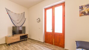 Una stanza con una porta in legno, un televisore su un supporto in legno e un elemento decorativo a parete.