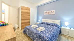 Una camera da letto con un letto, comodini, un tavolino notte, una porta in legno e vista sull'esterno.