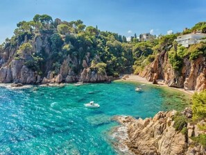 Un paysage côtier caractérisé par des falaises rocheuses, des eaux turquoise et limpides, et un bateau.