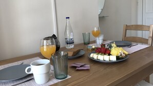 A breakfast table with a plate of fruit, a bottle of water, and glasses of orange juice. - Omega Comfy Apartments (Apokoronas)