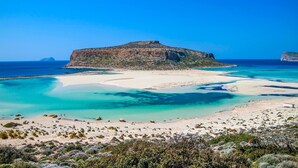 A coastal landscape with a prominent hill, clear turquoise waters, and sparse vegetation. - Omega Comfy Apartments (Apokoronas)