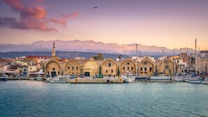 A harbor with boats, a mosque, and mountains in the background. - Omega Comfy Apartments (Apokoronas)