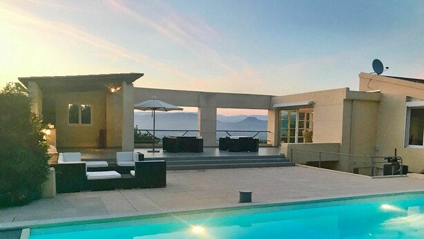 Un espace piscine extérieur moderne, doté de chaises longues et offrant une vue sur les montagnes.