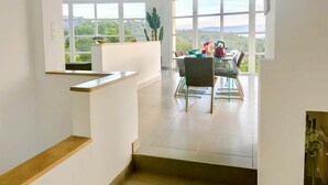 Une cuisine moderne avec un coin repas, de grandes fenêtres et une vue sur la verdure.