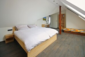 Ein modernes Schlafzimmer mit einem hölzernen Bett, einem Schreibtisch und einem Bücherregal.