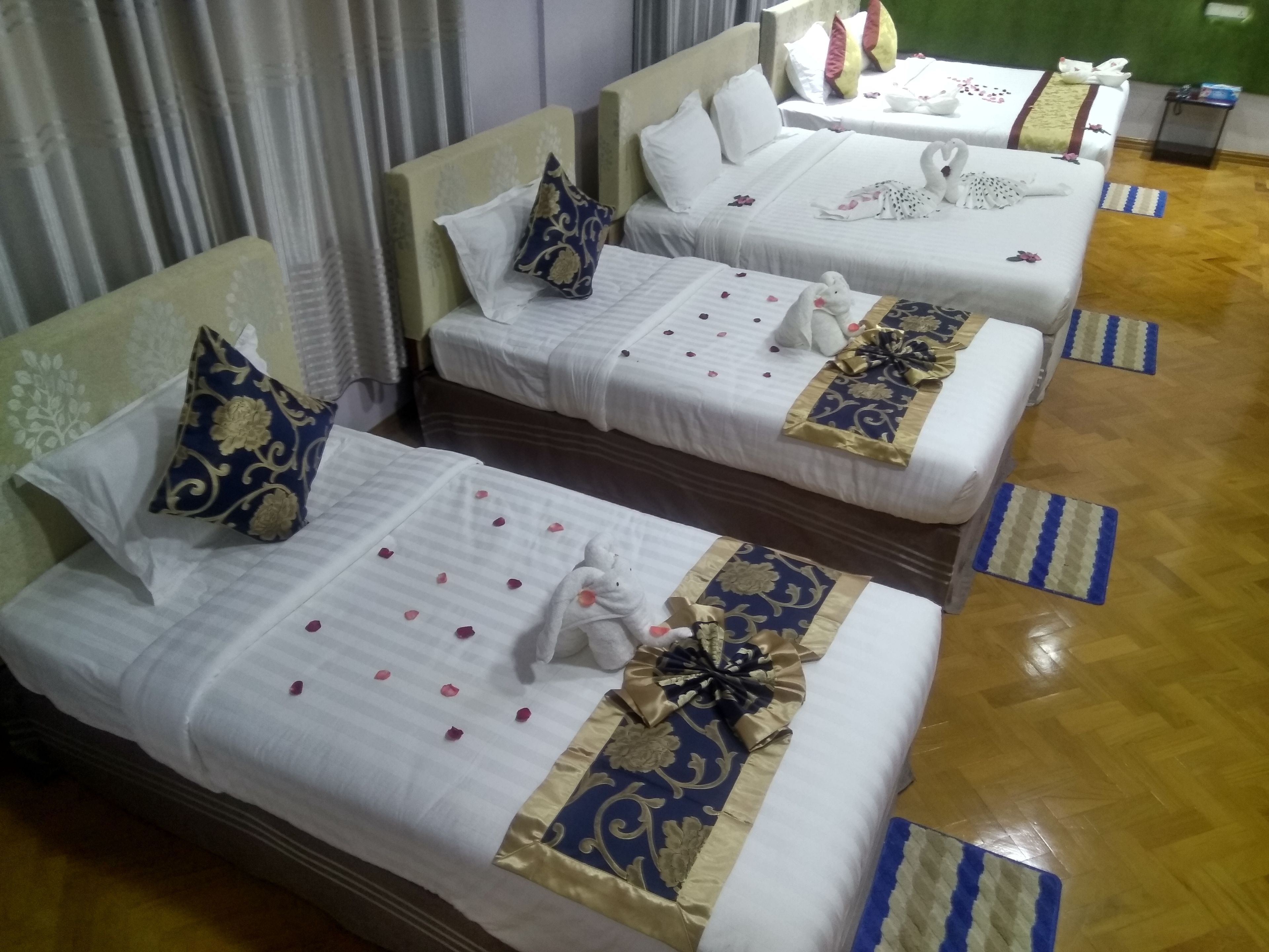 A hotel room with two beds, each with white bedding, decorative pillows, and floral arrangements.