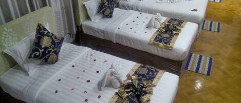 A hotel room with two beds, each with white bedding, decorative pillows, and floral arrangements.