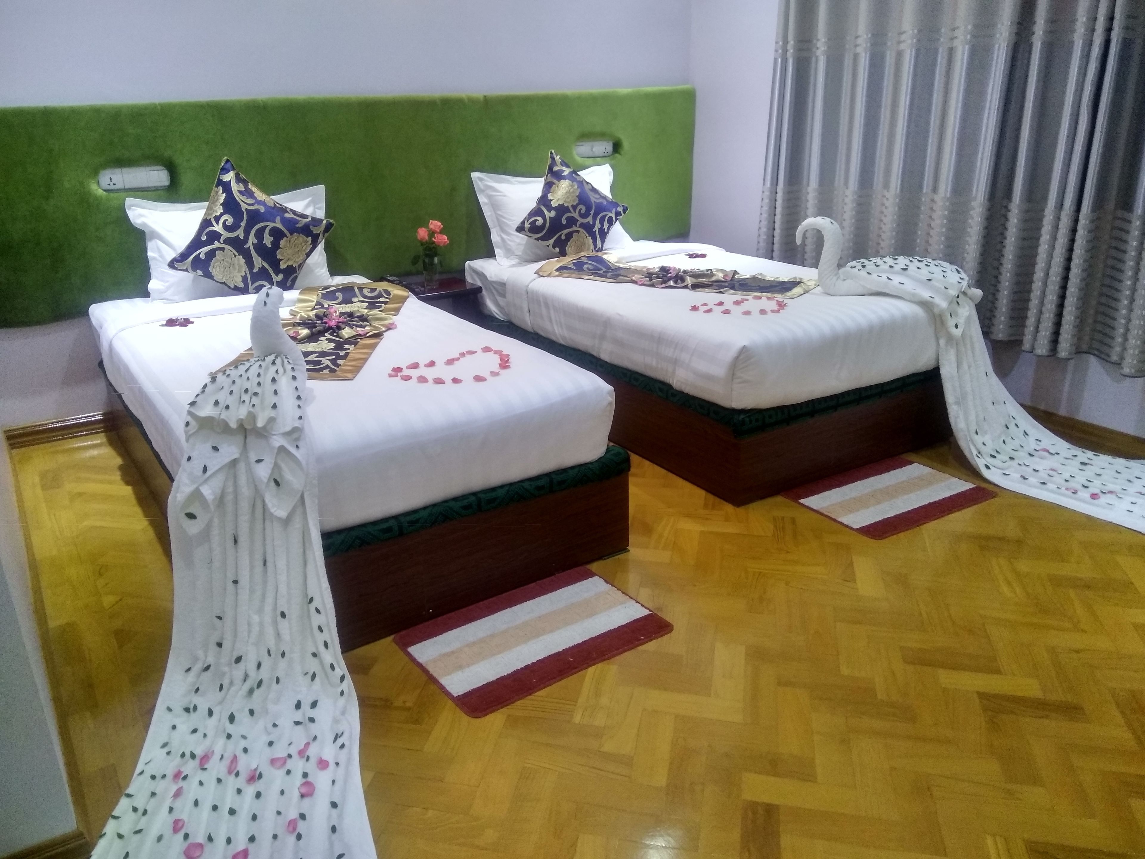 Dos camas individuales con cabeceros verdes, ropa de cama blanca y almohadas decorativas.