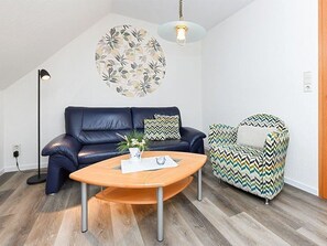 Ein modernes Wohnzimmer mit einem dunkelblauen Sofa, einem gemusterten Sessel und einem Holztisch.