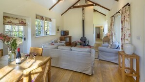 A cozy living room with a fireplace, sofas, a dining table with wine glasses, and a TV.