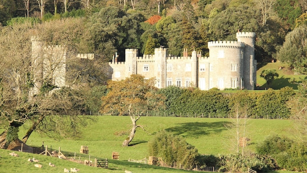 A castle with a tower, surrounded by a green landscape and trees.