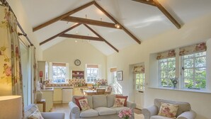 A spacious living room with a high ceiling, a cozy fireplace, and a view of the kitchen and dining area.