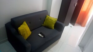 Ein dunkelgraues Sofa mit zwei gelben Kissen und einer Fernbedienung darauf.