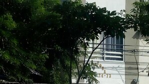 Ein modernes Gebäude mit Flachdach, großem Fenster mit Vorhängen und einer sichtbaren Hausnummer.