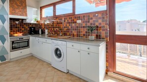 Une cuisine moderne équipée d’un four encastré, d’un lave-linge et d’un évier.