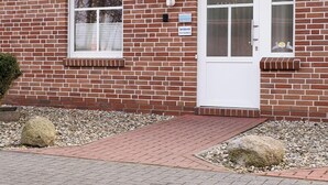 Ein zweistöckiges Ziegelhaus mit rotem Ziegeldach, zwei Dachfenstern und einer weißen Tür.