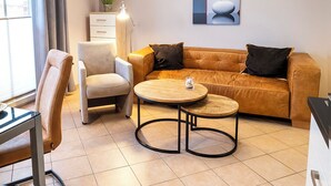 Ein modernes Wohnzimmer mit Sofa, Sessel und rundem Couchtisch.