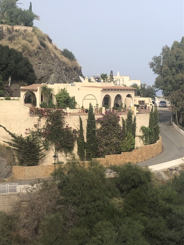 A building with multiple arches, a stone wall, and potted plants.