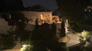 Un edificio con ventanas de arco y un sendero que lo conduce, rodeado de árboles.