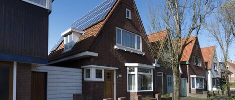A residential house with a sloped roof, solar panels, and a garage.