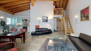 A spacious living area with a high ceiling, a dining table, a sofa, and a staircase leading to an upper level. - Traditional nice apartment house in good location. (Celerina/Schlarigna)
