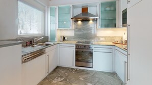 A modern kitchen with white cabinets, a stainless steel range hood, a built-in oven, and a dishwasher. - Traditional nice apartment house in good location. (Celerina/Schlarigna)