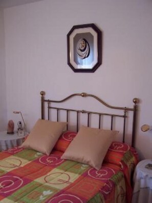 Ein Bett mit Metallgestell, zwei Kissen und einer bunten Steude.