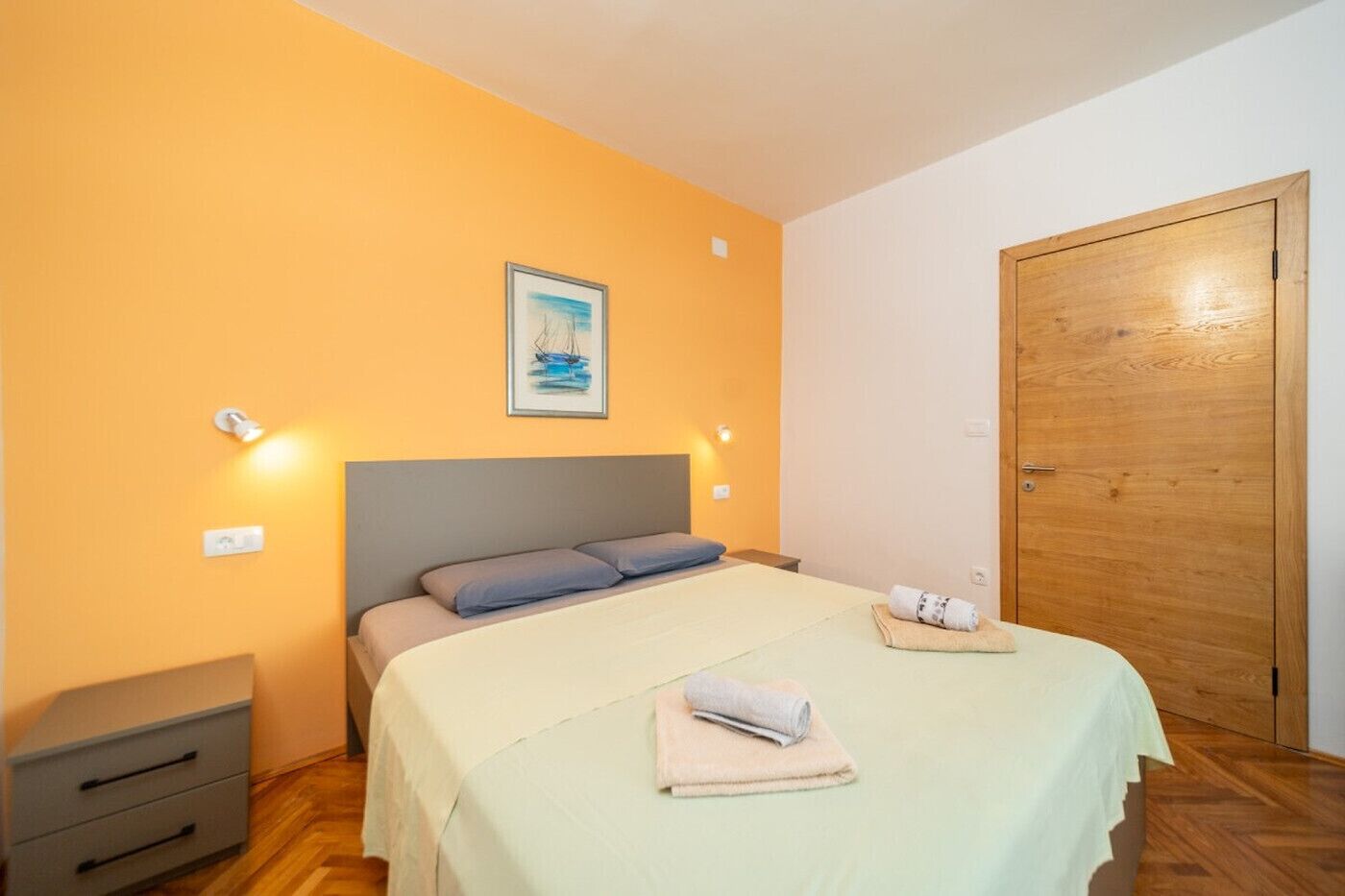 Ein Schlafzimmer mit einem Bett, einer Holztür und einem Gemälde an der Wand.