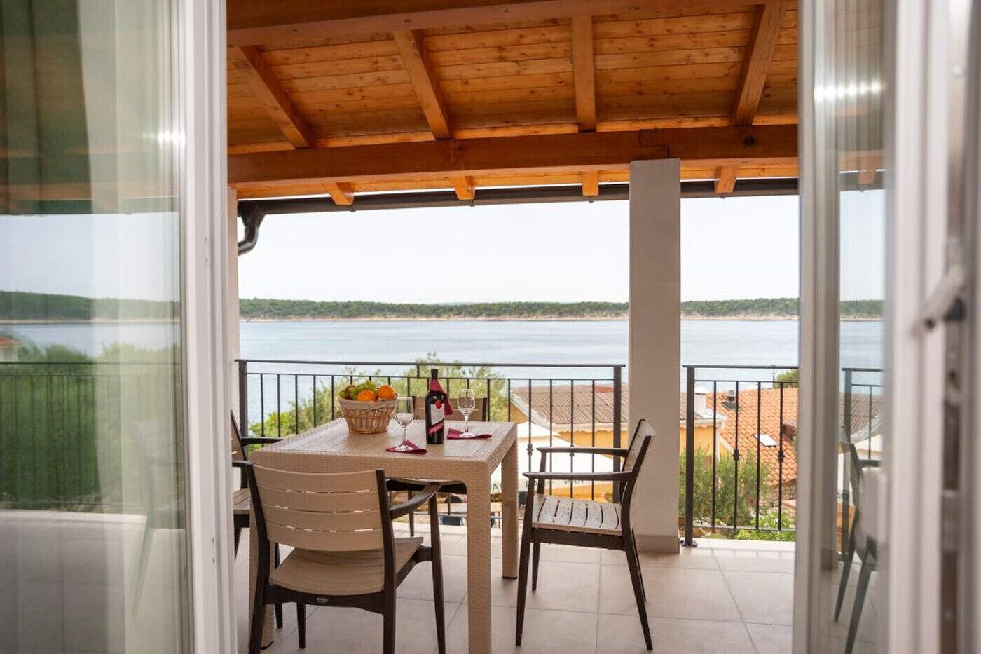 A balcony with a table set for two, overlooking a body of water.
