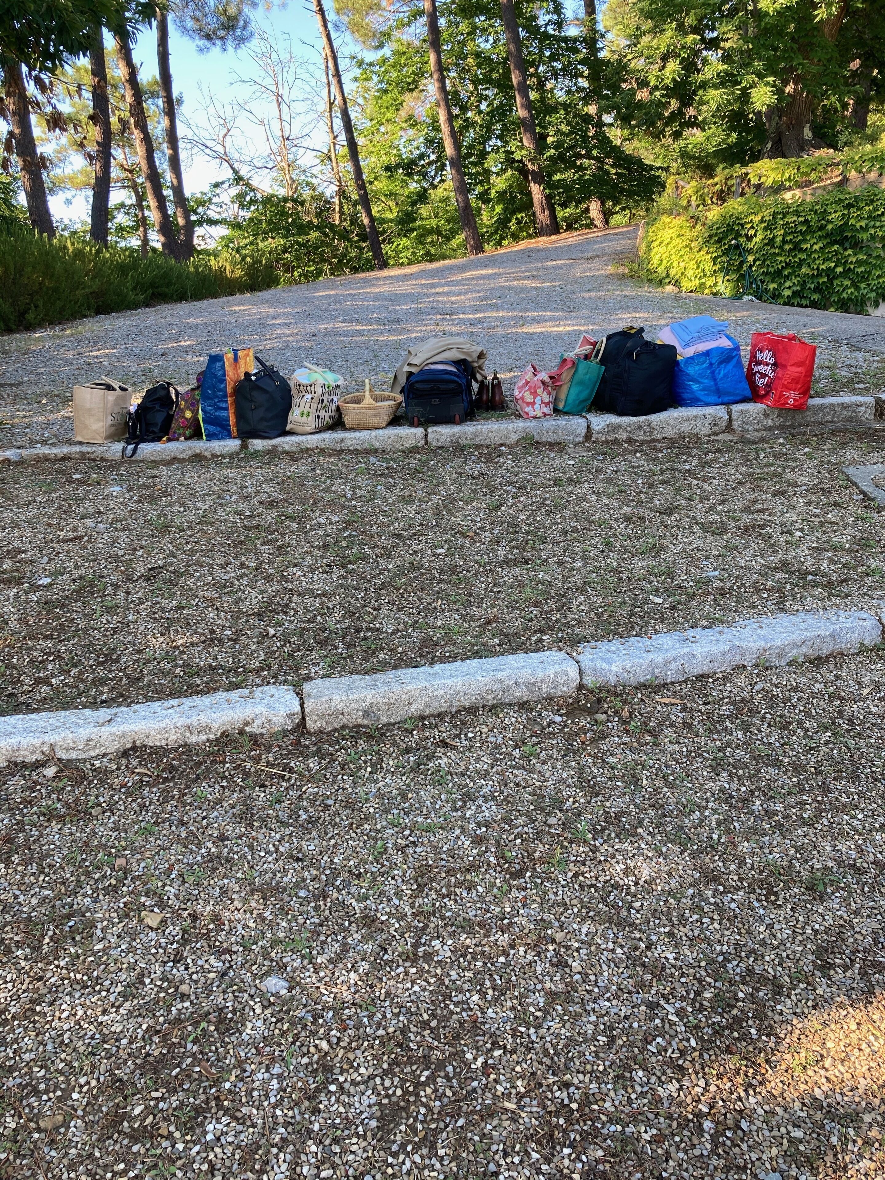 A gravel area with various bags and a red shopping bag.